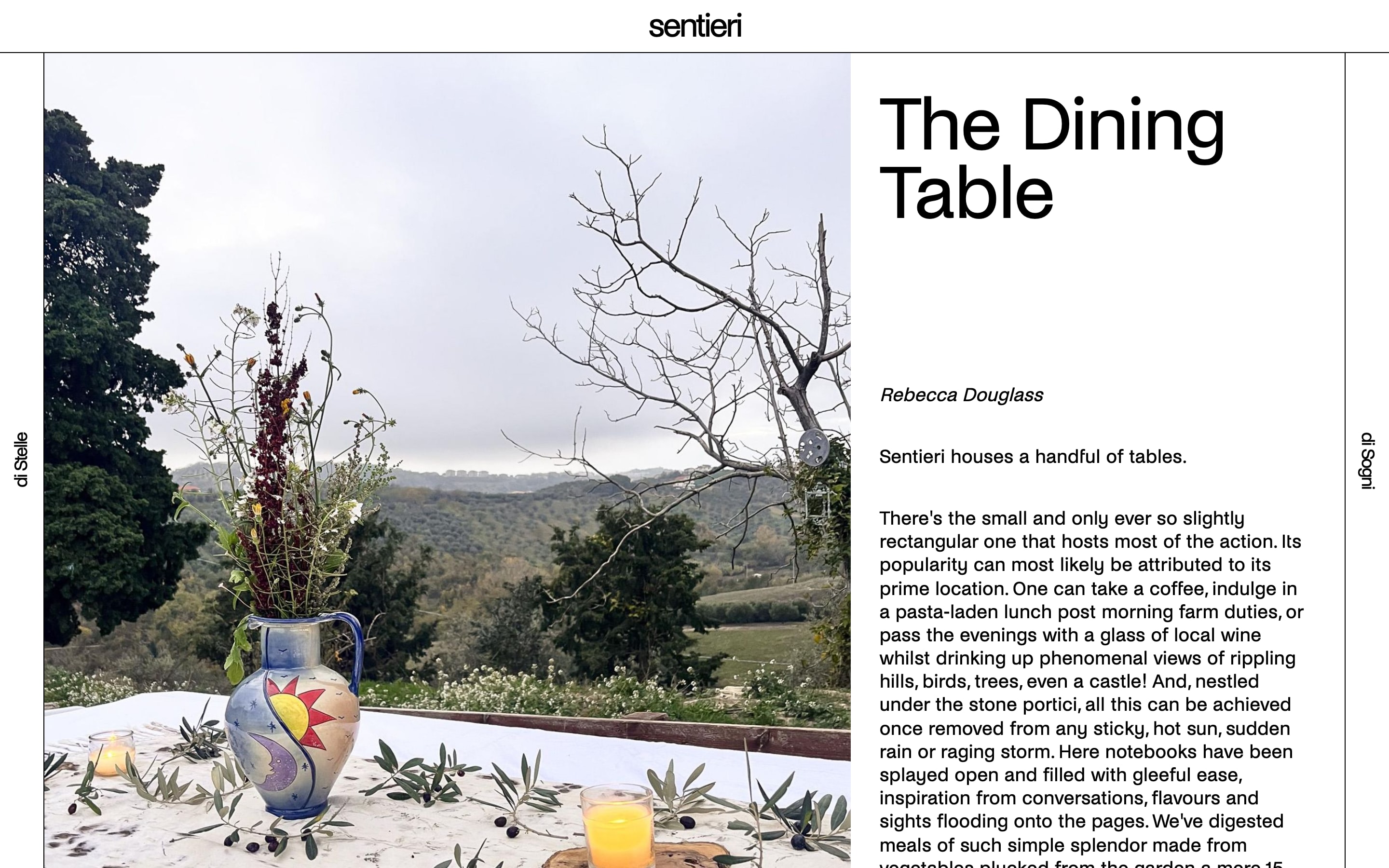 An article page of sentieri.co titled The Dining Table. The photograph is on the left: a painted jug of wild flowers and a glass of juice on a white cloth scattered with olives, hills behind. The text pane is on the right, with the title in large type, the author's name in italics and the opening paragraphs.